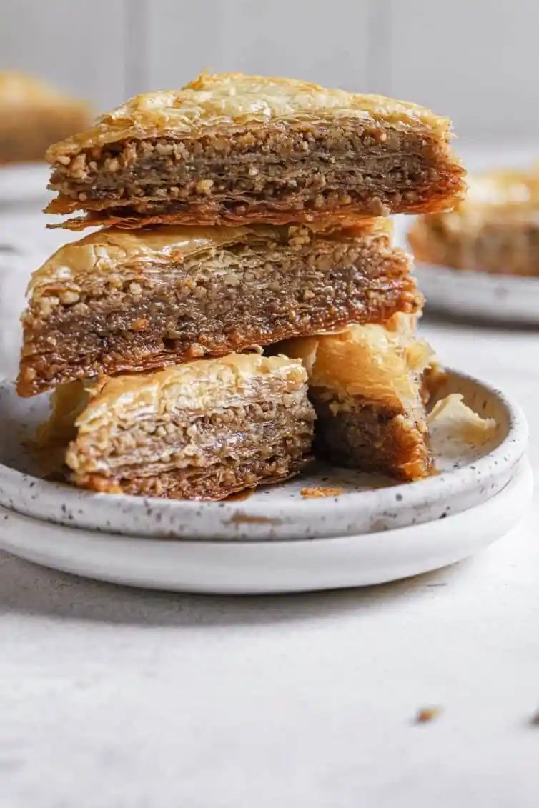 A stack of baklava triangles on white plates.
