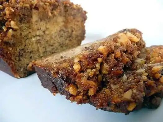 Loaf of bananas foster banana bread with 2 slices of bread on a white plate.