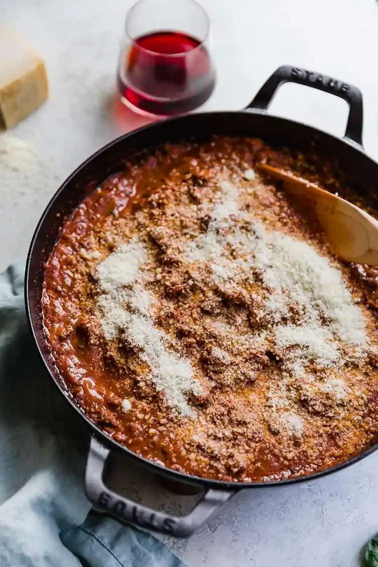 A pan of bolognese sauce with grated Parmesan cheese added.