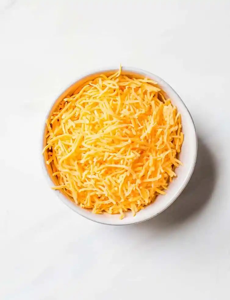 A prep bowl with shredded cheddar cheese.