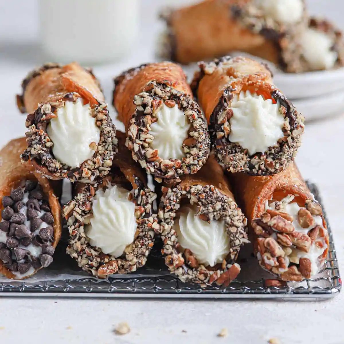 Two rows of from-scratch cannoli stacked on each other on top of a cooling rack.