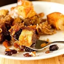Serving of Mexican bread pudding on a white plate with a fork.