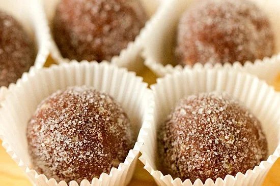 Individual chocolate bourbon balls placed in white candy wrappers.