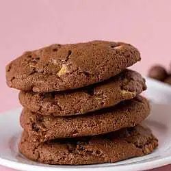 Stack of 4 chocolate malted whopper cookies on a white plate.