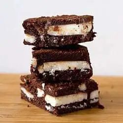 Stack of 3 chocolate mint brownies on a wood surface.
