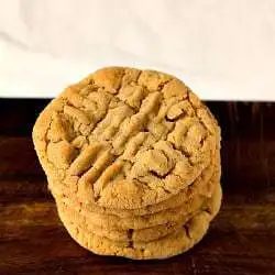 Stack of peanut butter cookies on a wood board.