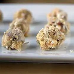 Date, coconut, and walnut truffles on a ceramic serving tray.