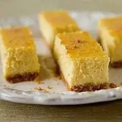 Side view of eggnog cheesecake bars on a white plate.