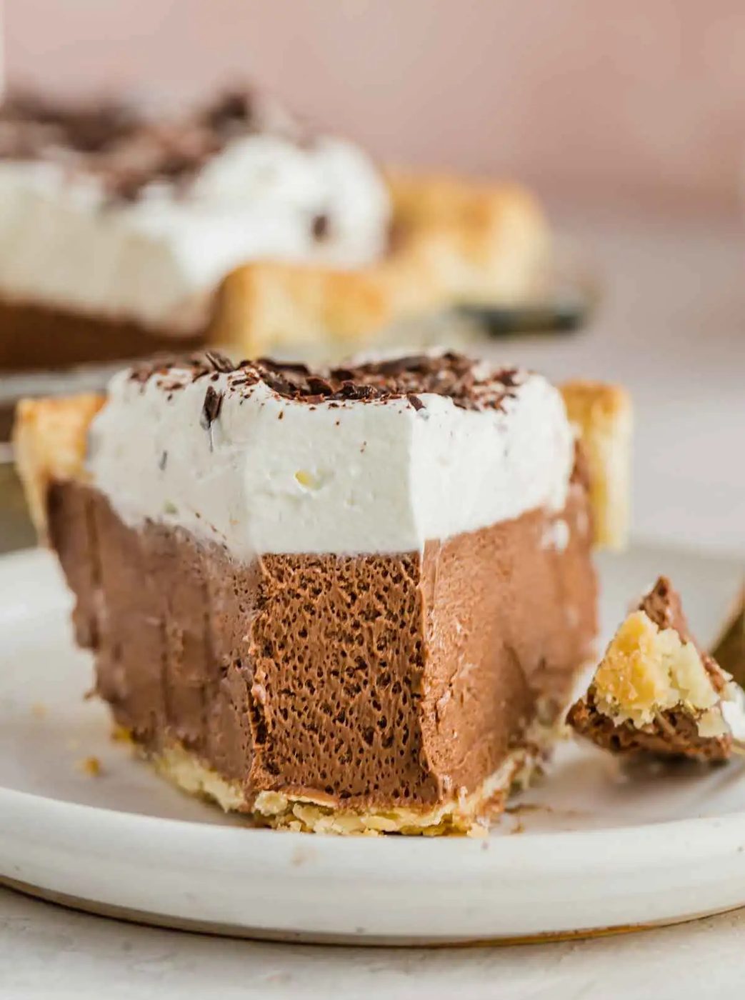 Head-on closeup photo of French silk pie on a white plate with forkful removed from front.
