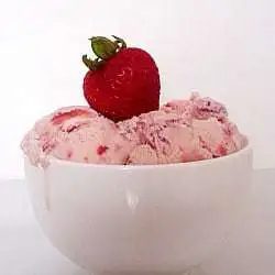 Scoops of strawberry ice cream in a white bowl topped with a fresh strawberry.