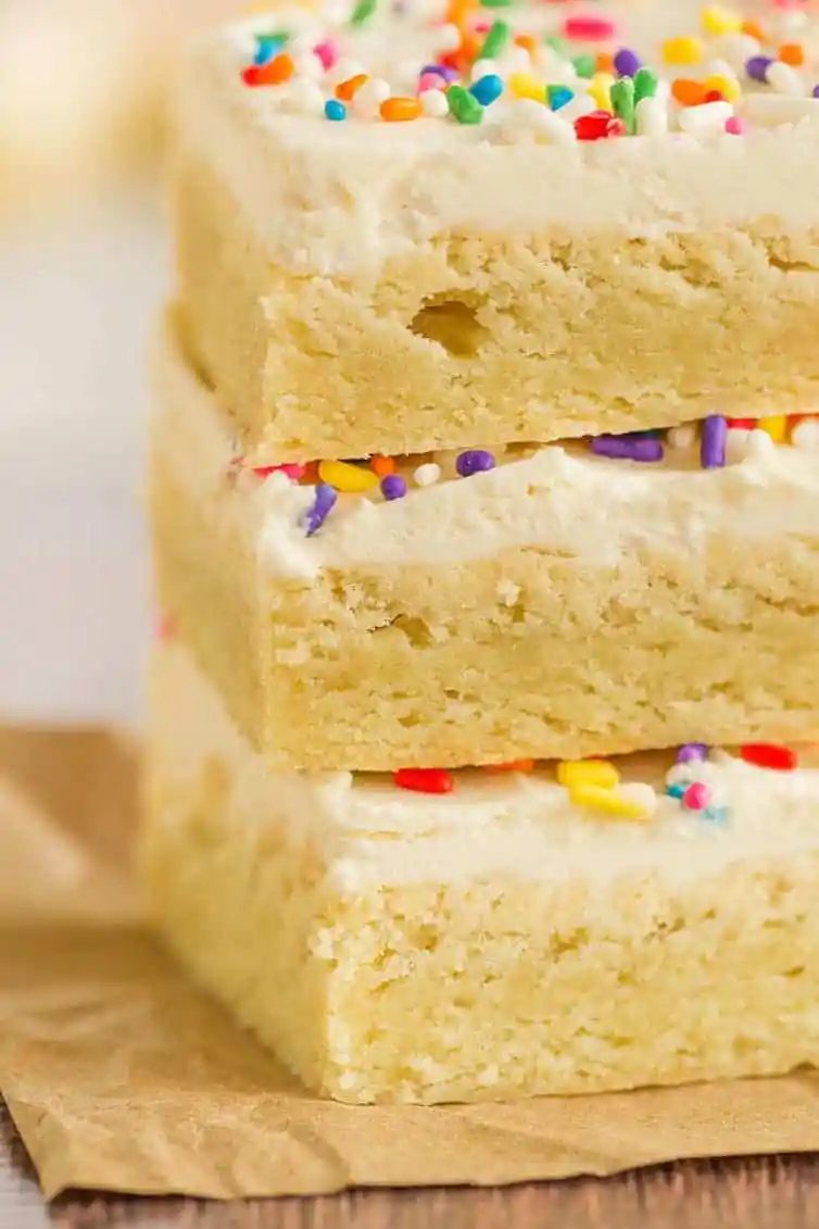 A close-up shot of a stack of frosted sugar cookie bars.