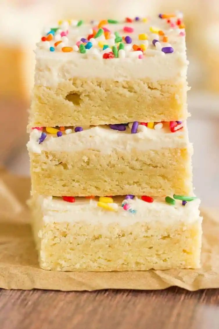A stack of three sugar cookie bars with frosting and sprinkles.