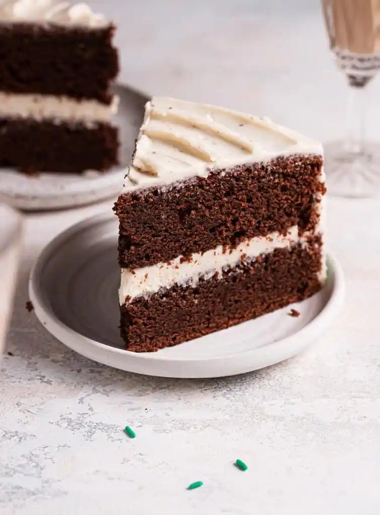 A slice of Guinness chocolate cake on a white plate with a second slice behind.