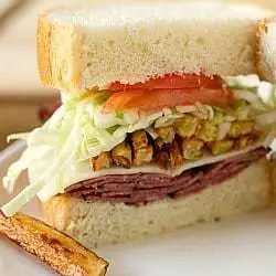 A from-scratch primanti brother's sandwich cut in half showing all of the sandwich ingredients.