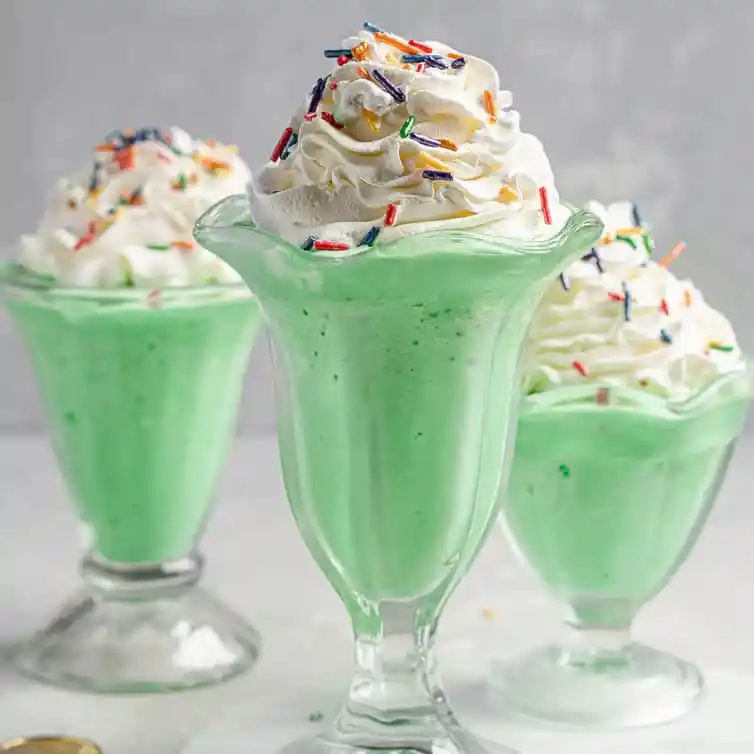 Three milkshake glasses filled with at-home McDonald's shamrock shakes.
