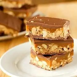 Stack of 3 from-scratch Snickers bars on a white plate.