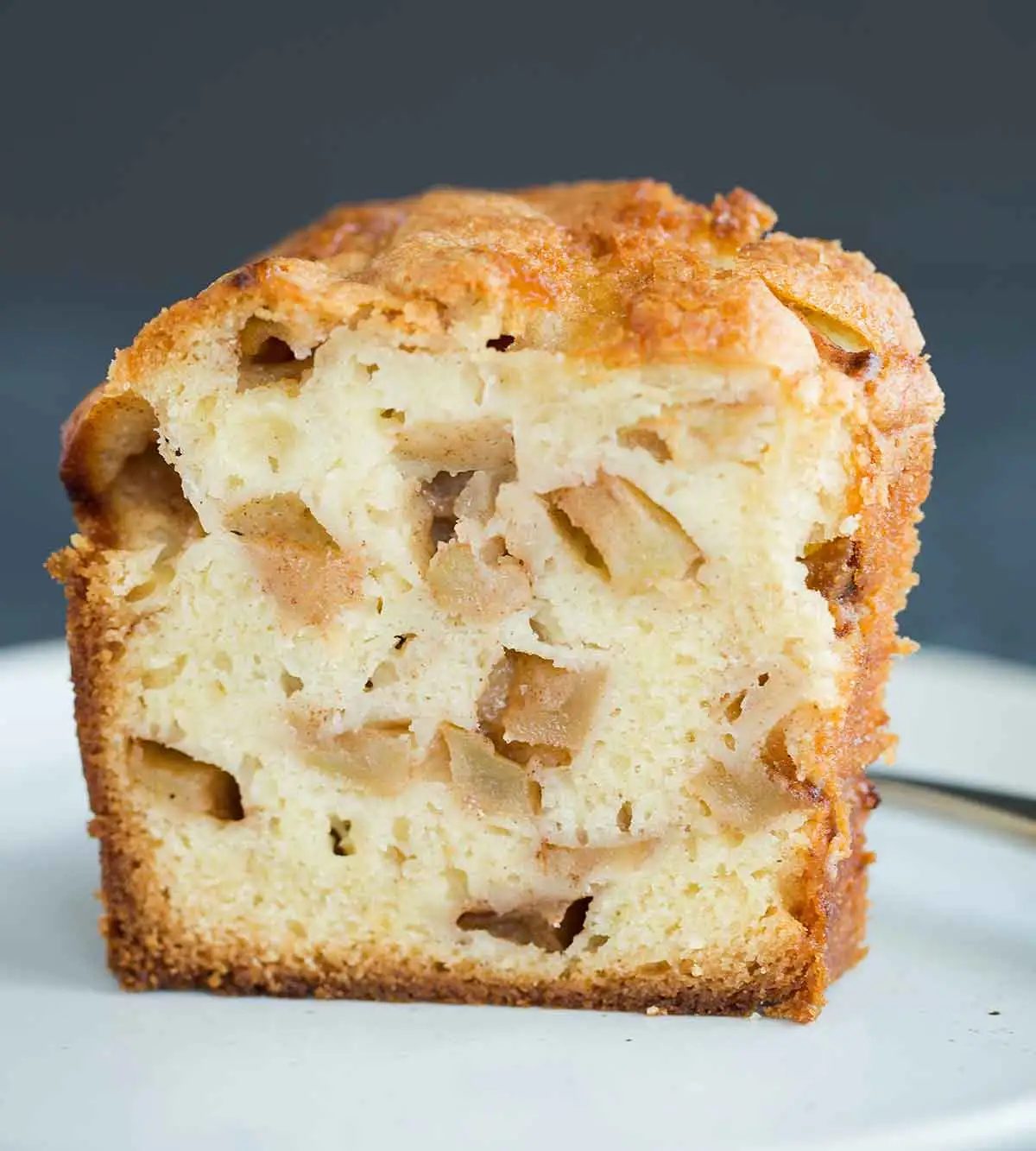 Slice of Jewish apple cake studded with chunks of cinnamon-sugar coated apples.