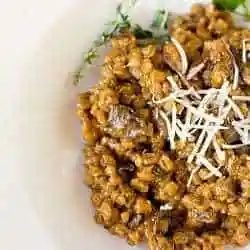 A serving of mushroom barley risotto on a white plate.
