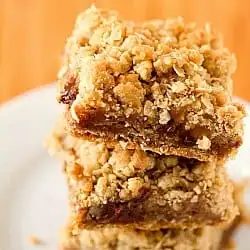 Stack of oatmeal carmelita bars on a white plate.