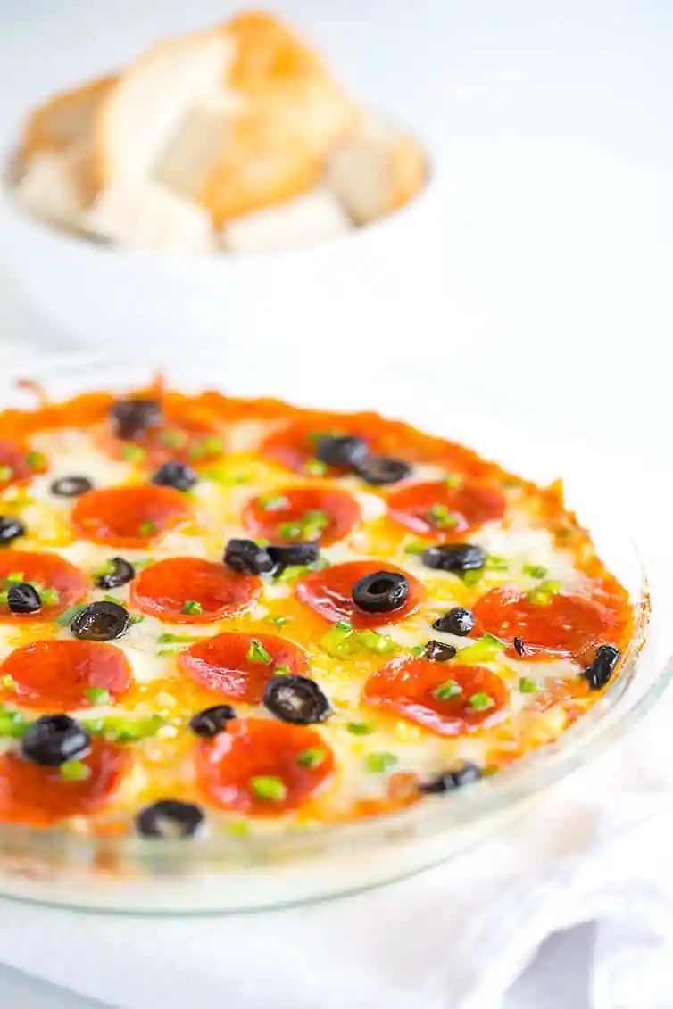 A pie plate with pizza dip and a bowl of bread cubes for dipping.