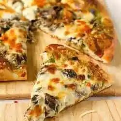 Slices of portobello pesto pizza on a wood cutting board.