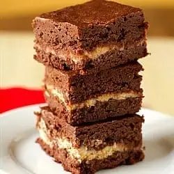 Stack of 3 raspberry cream cheese brownies on a white plate.