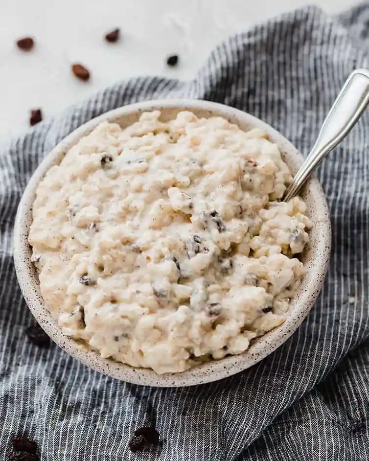 A bowl of rice pudding with raising on a dish towel.
