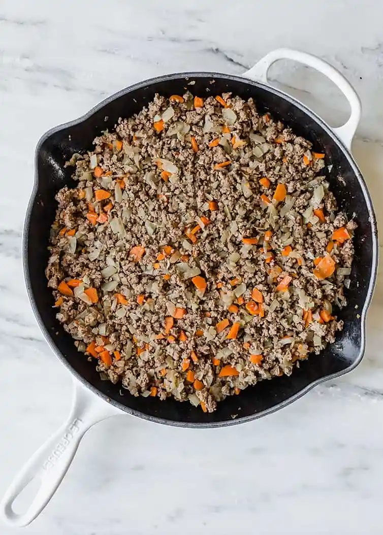 A skillet with the cooked meat mixture for shepherd's pie.