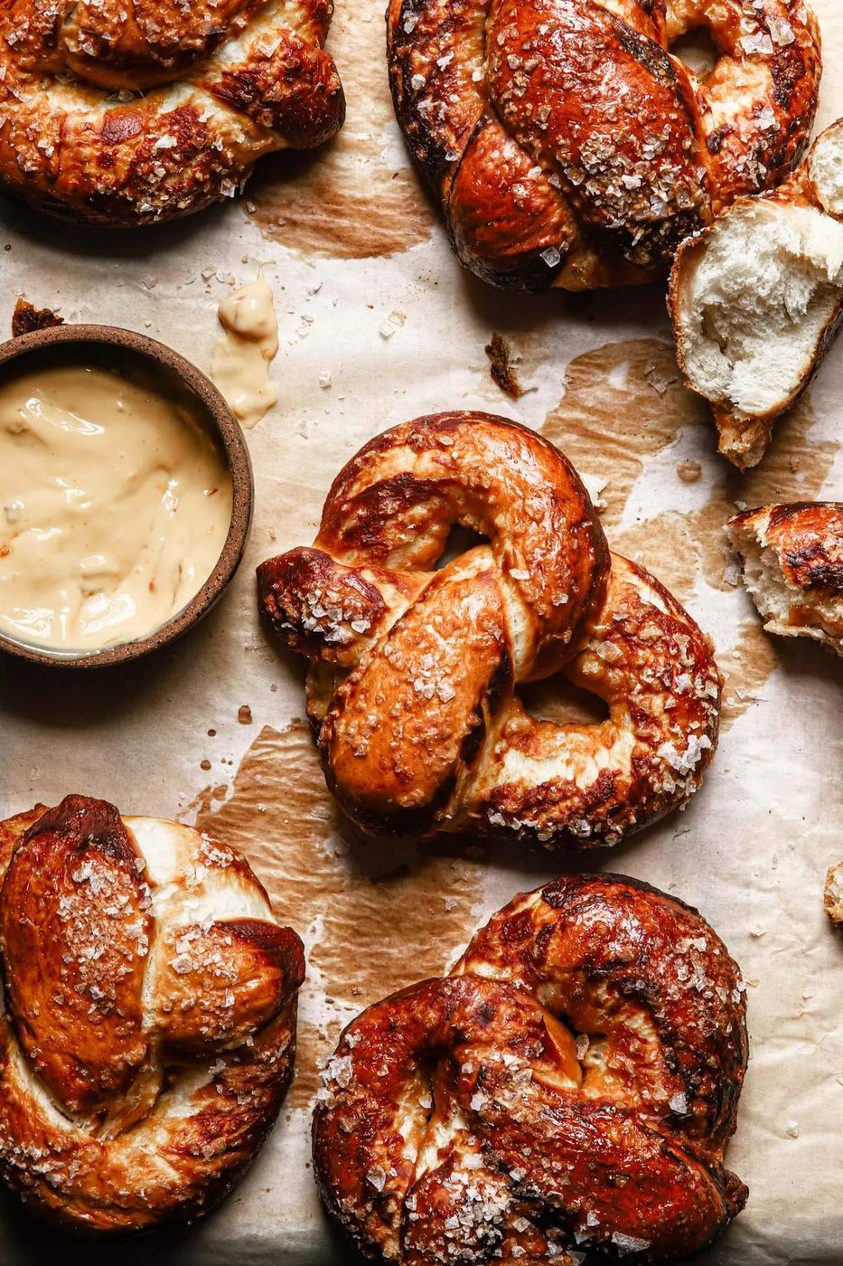 from-scratch soft pretzels on a baking tray garniched with coarse salt and with a beer cheese dipping sauce on the side