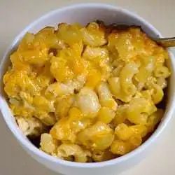Baked macaroni and cheese in a white bowl with a spoon.