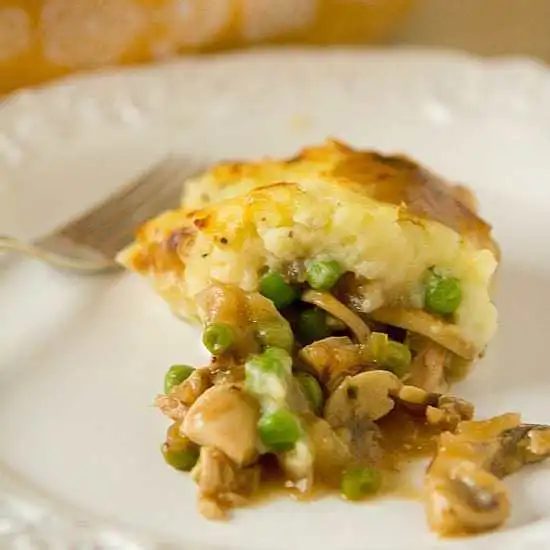 Serving of turkey pot pie on a white plate with a fork.