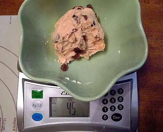 Green bowl with a scoop of ice cream in it on a food scale.