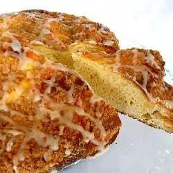 Coffee cake with icing on a glass serving platter with a slice removed.