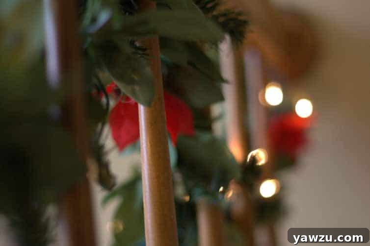 A beautifully lit garland draped along a wooden stairway railing, creating a warm, cozy, and inviting Christmas atmosphere indoors.