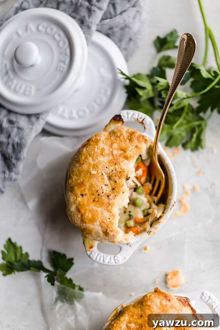 An overhead shot of a half-eaten ramekin of chicken pot pie.