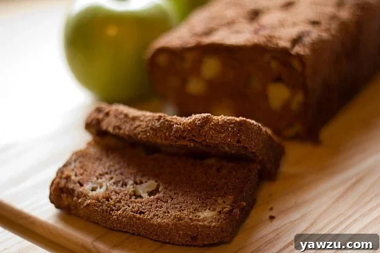 Two slices of tender apple cinnamon bread cut from a freshly baked loaf, presented on a rustic wooden cutting board, ready to be enjoyed.