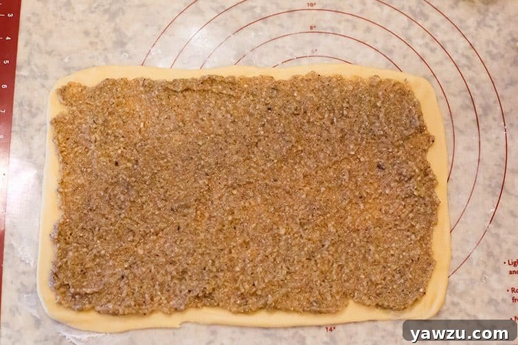 Nut filling generously spread on perfectly rolled out dough, ready for shaping.