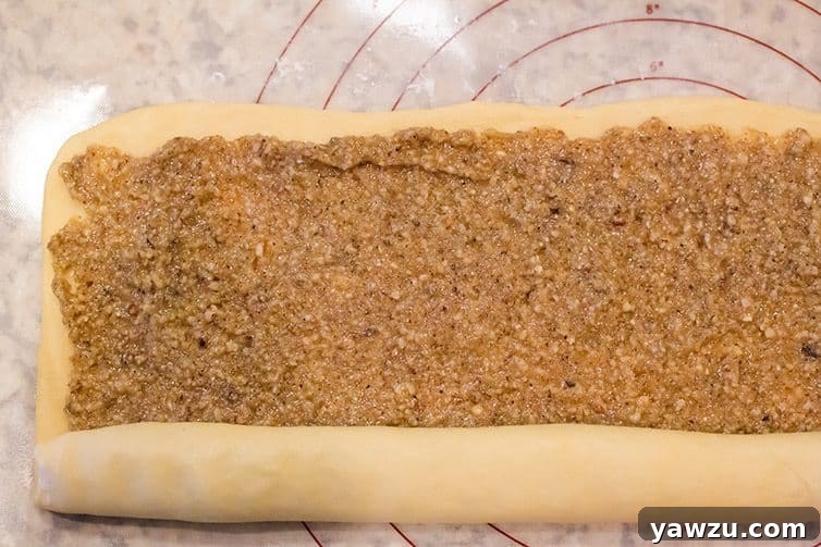 A nut roll being carefully rolled up, showcasing the even distribution of the delicious filling.