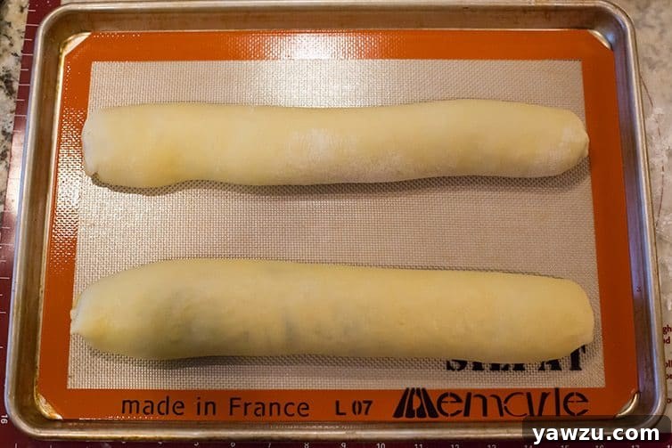 Assembled nut rolls neatly placed on a baking sheet, ready for their final rise and oven bake.