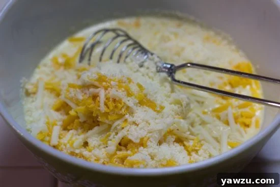 Cheese sauce ingredients in a bowl with a whisk.