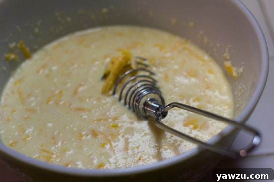 Cheese sauce in a saucepan with a whisk.