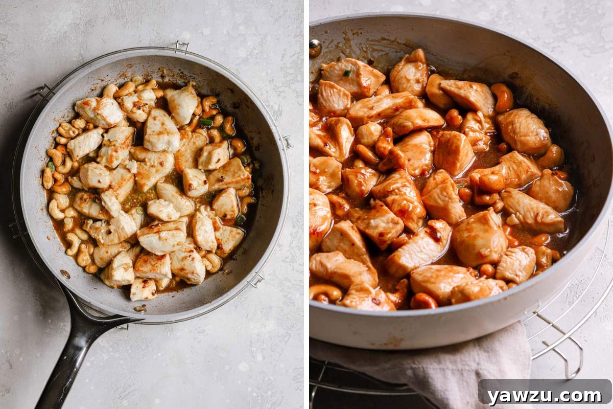 Chicken and cashews in a frying pan with a thick sauce.