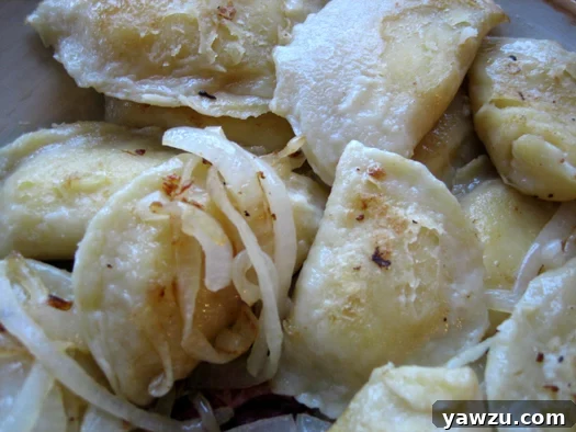 A generous platter of homemade pierogies, ready to be served, glistening with fried onions.