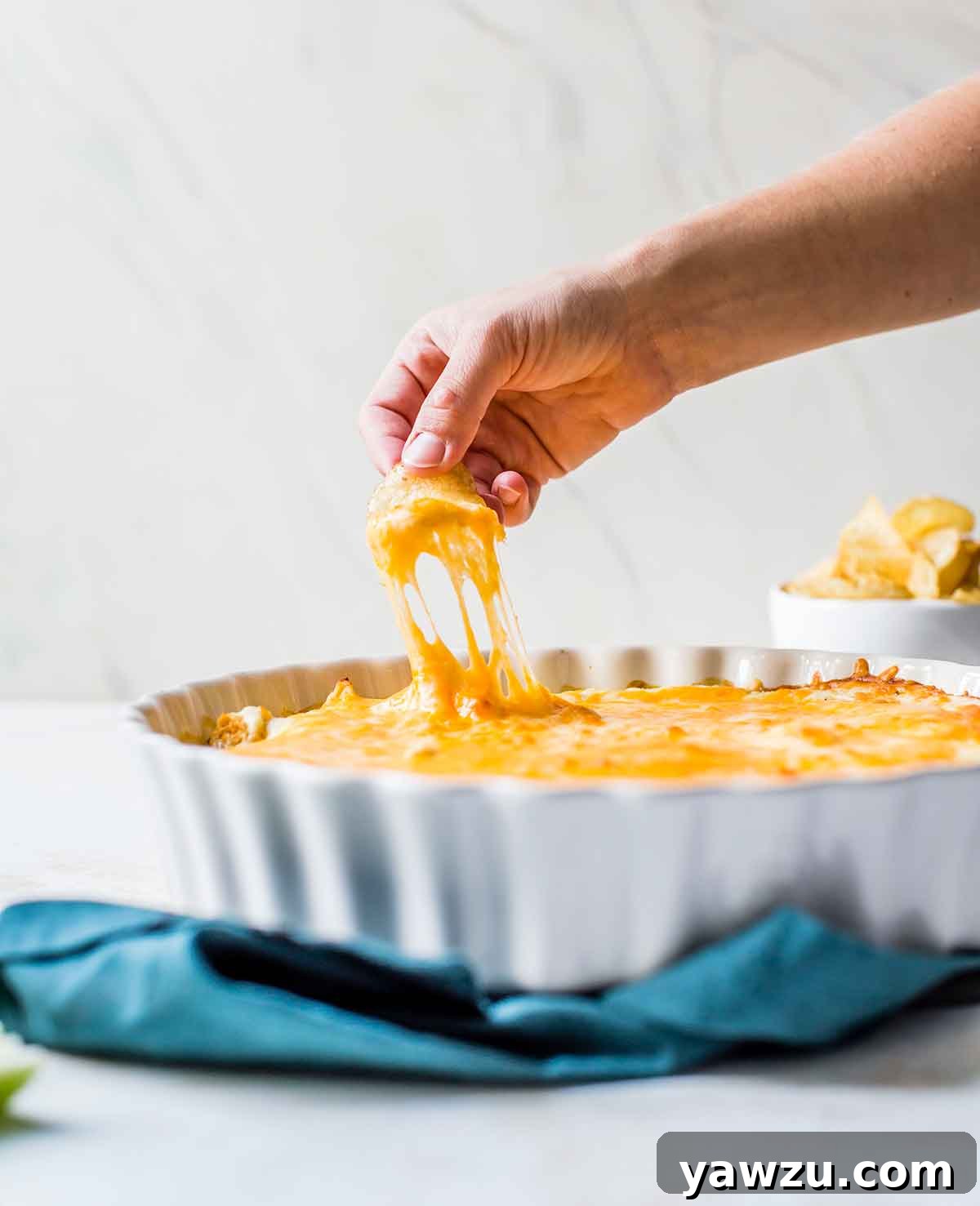 Someone pulling up a scoop of buffalo chicken dip on a potato chip.