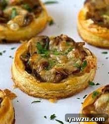 Caramelized onion, mushroom, and gruyere tartlets on a white serving plate.