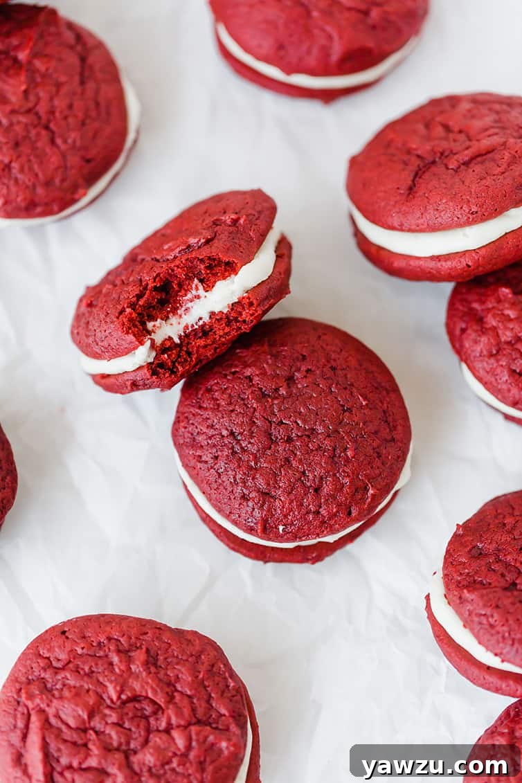 An overhead shot of red velvet whoopie pies arranged on a white surface, highlighting their vibrant color and creamy texture.