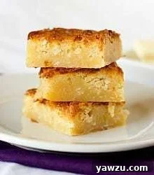 Stack of 3 white chocolate coconut brownies on a white plate, showcasing their delightful appearance.