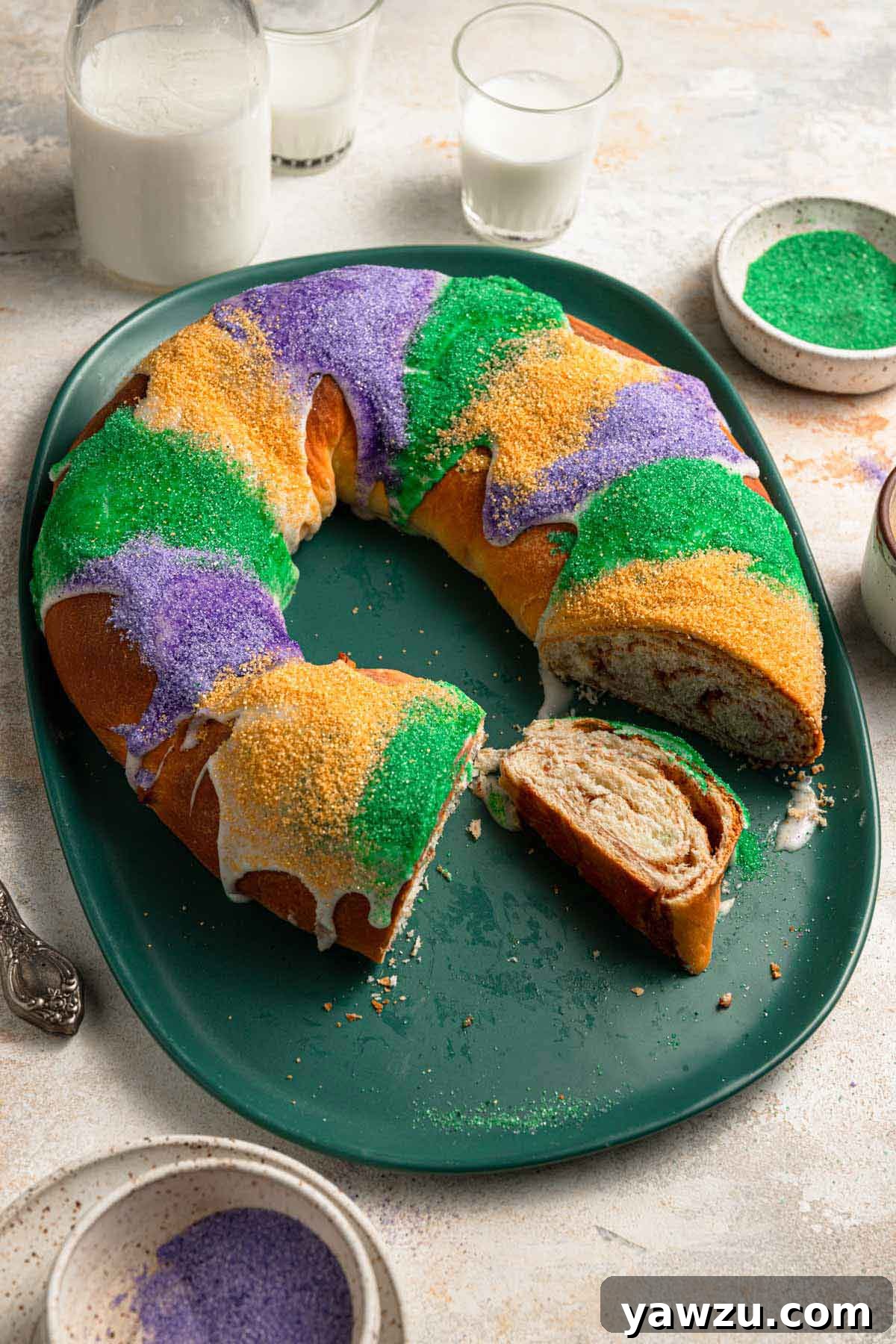 King cake on a platter with a number of slices removed and one on the platter on its side.