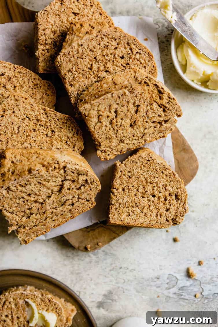 Sliced Irish brown bread on a wooden cutting board with a small bowl of butter to the right.