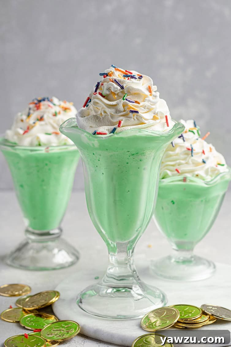 Three milkshake glasses filled with green shamrock shakes, ready to be enjoyed.